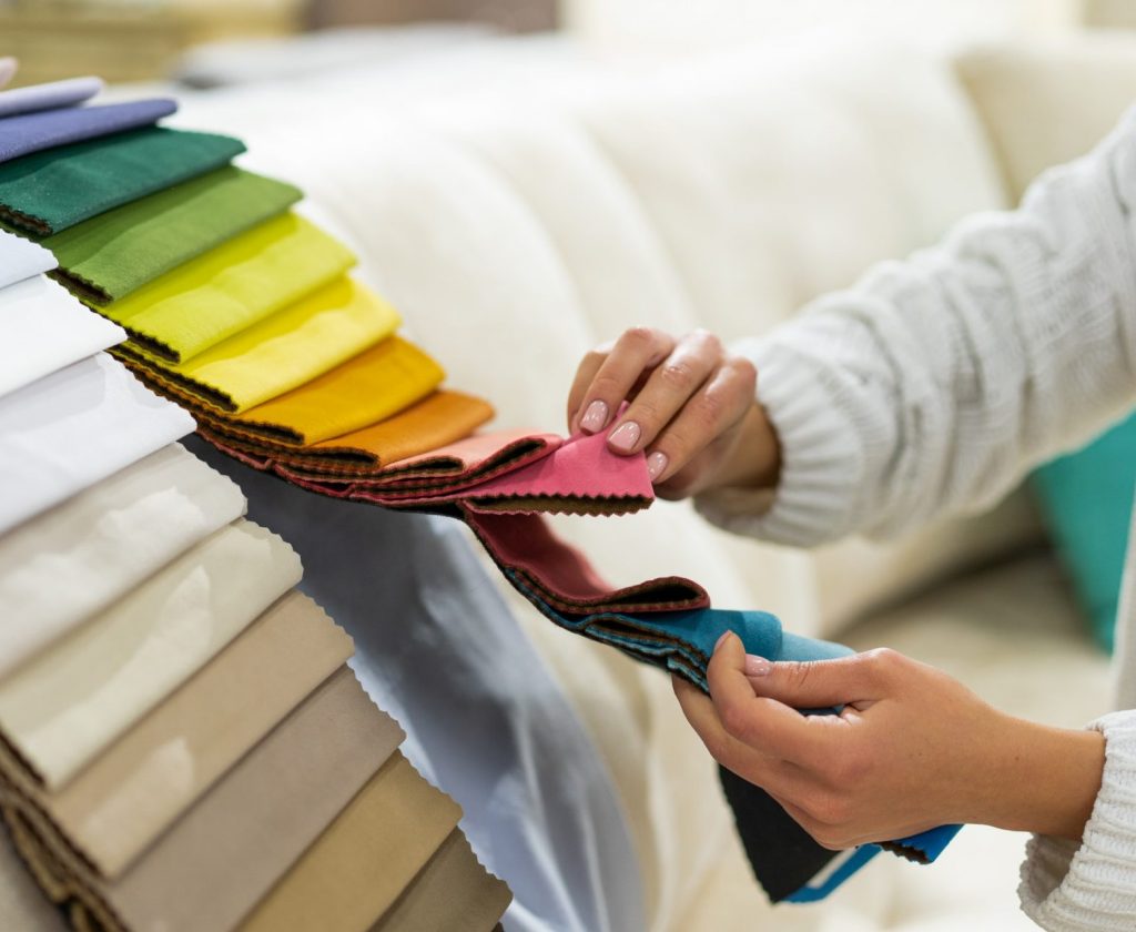 The woman chooses the fabric on the sofa. Textile industry background. Tissue catalog